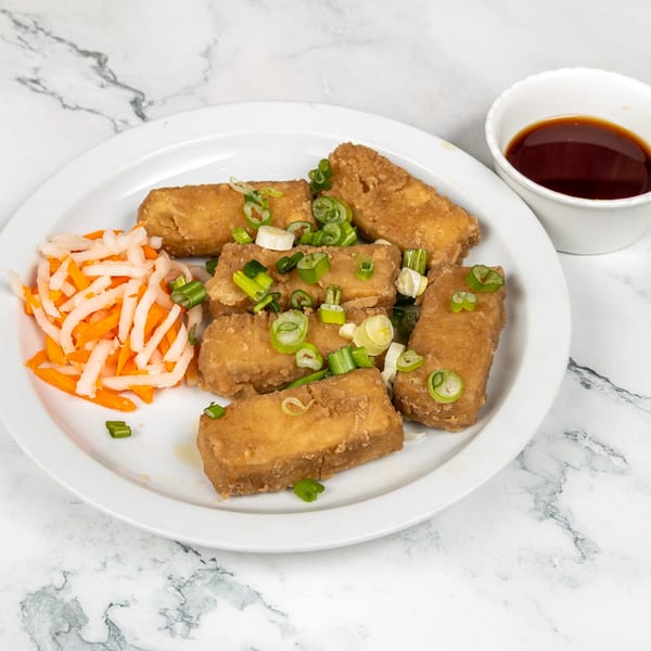 Fried tofu with green onions, pickled carrots, daikon, and a side of soy sauce.