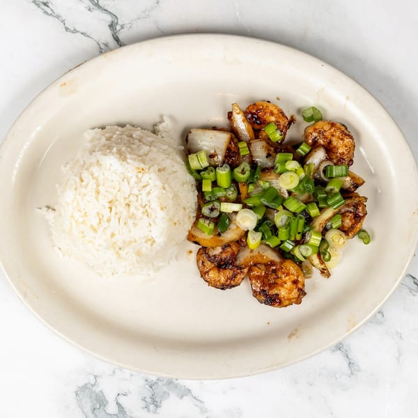 Vietnamese shrimp with onions and scallions, served with white rice on a white plate.