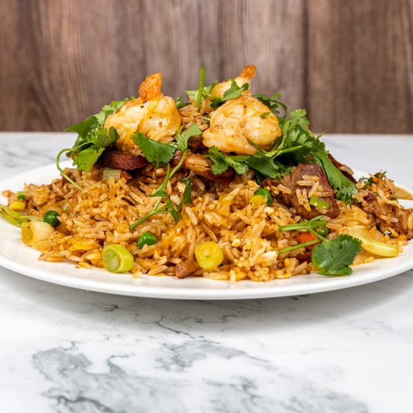 Vietnamese fried rice with shrimp, beef, peas, and cilantro on a white plate.